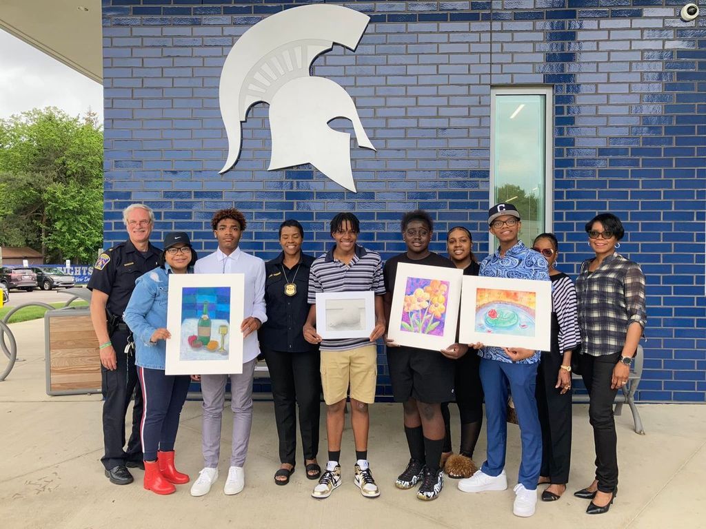 students posing in a group with their artwork