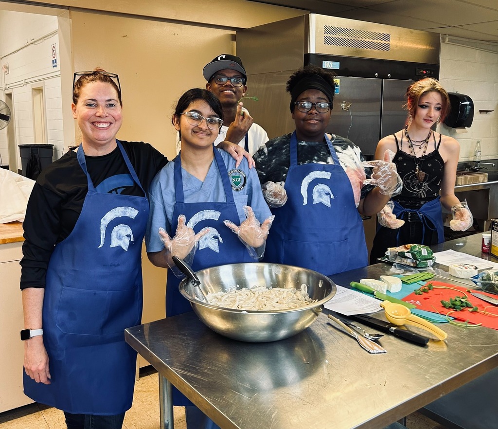 photo of culinary students and their teacher wearing Spartan Nation aprons preparing meals in the kitchen